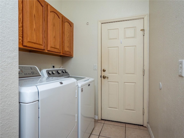 washroom featuring washer and dryer, cabinets, and light tile patterned floors