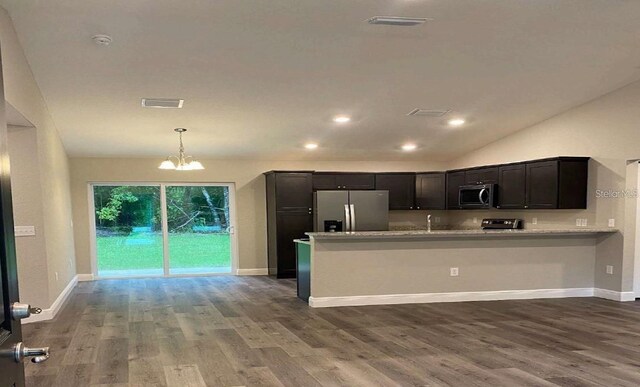 kitchen featuring light stone countertops, appliances with stainless steel finishes, kitchen peninsula, a chandelier, and dark hardwood / wood-style floors