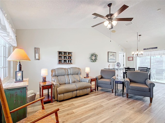 living room featuring ceiling fan with notable chandelier, a textured ceiling, vaulted ceiling, and light hardwood / wood-style flooring