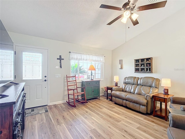 living room with a textured ceiling, light hardwood / wood-style flooring, ceiling fan, and lofted ceiling