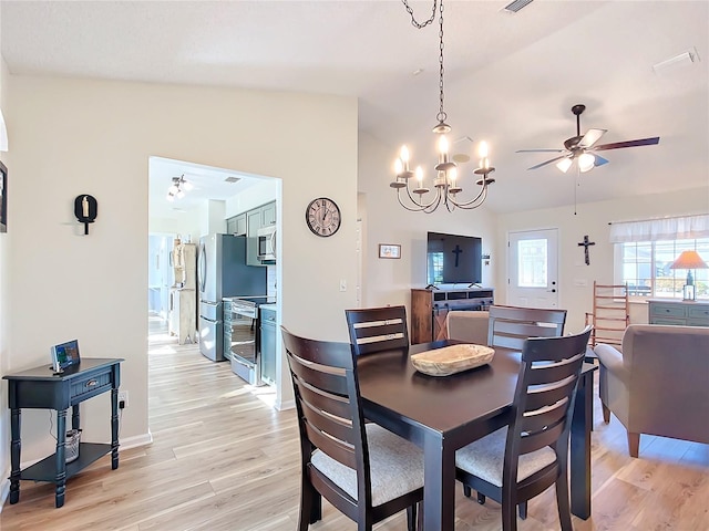 dining room featuring ceiling fan with notable chandelier, light hardwood / wood-style flooring, and vaulted ceiling