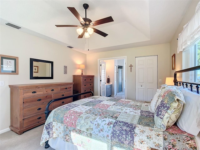 carpeted bedroom featuring a closet, ensuite bath, and ceiling fan