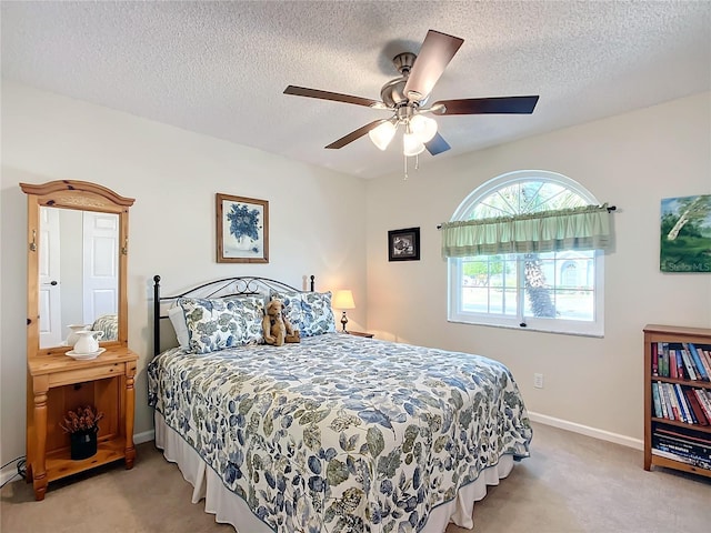 carpeted bedroom featuring ceiling fan and a textured ceiling