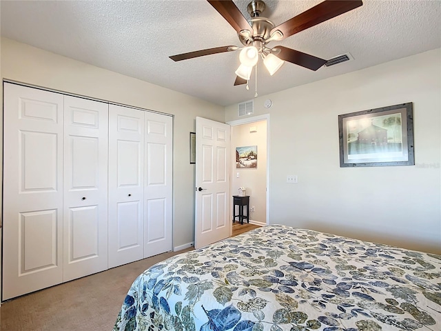 bedroom with ceiling fan, light colored carpet, a textured ceiling, and a closet