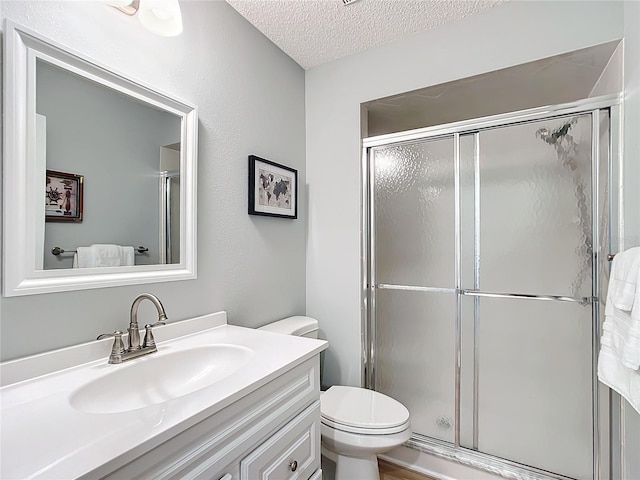 bathroom with vanity, a textured ceiling, toilet, and walk in shower