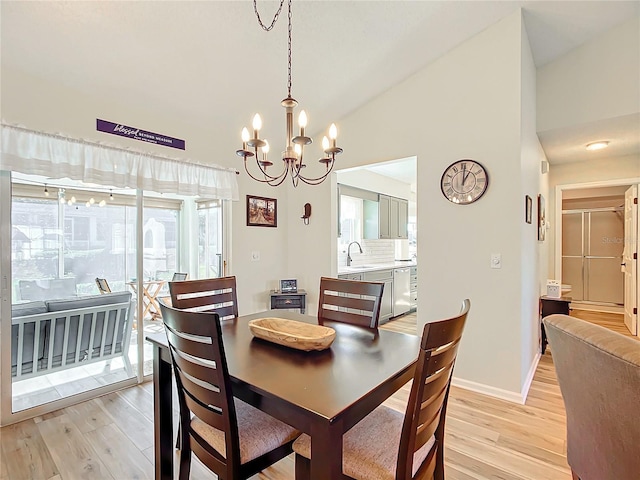 dining space featuring high vaulted ceiling, sink, a chandelier, and light hardwood / wood-style floors