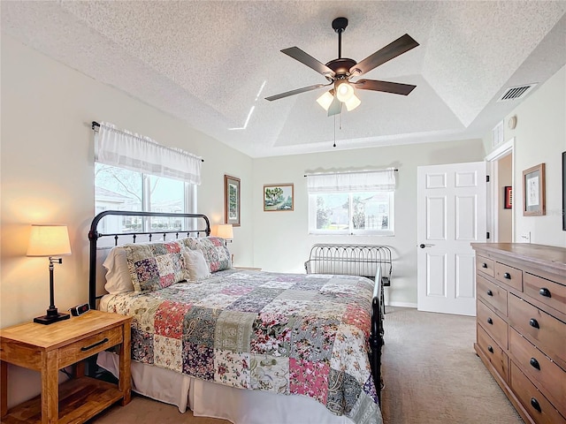 carpeted bedroom featuring a tray ceiling, a textured ceiling, and ceiling fan