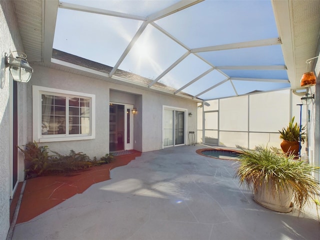 view of patio featuring glass enclosure and a jacuzzi