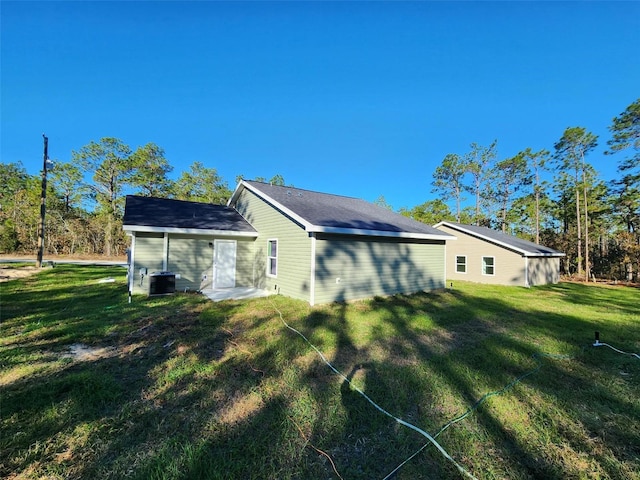 rear view of house with cooling unit and a lawn