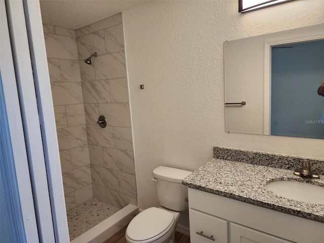 bathroom with vanity, toilet, and a tile shower