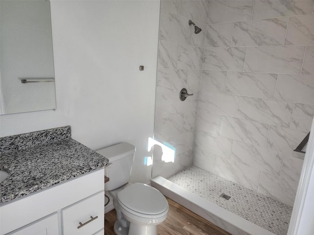 bathroom featuring tiled shower, wood-type flooring, vanity, and toilet