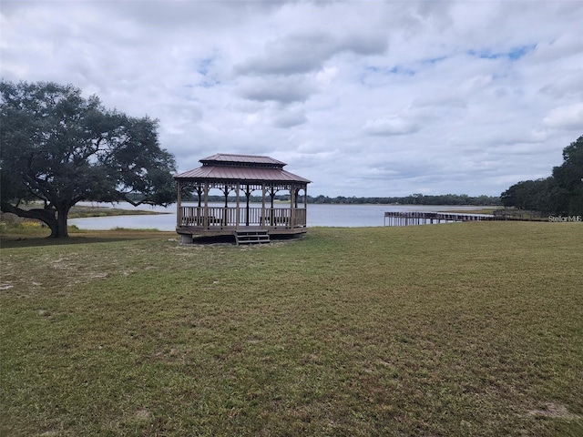 dock area featuring a gazebo, a water view, and a lawn