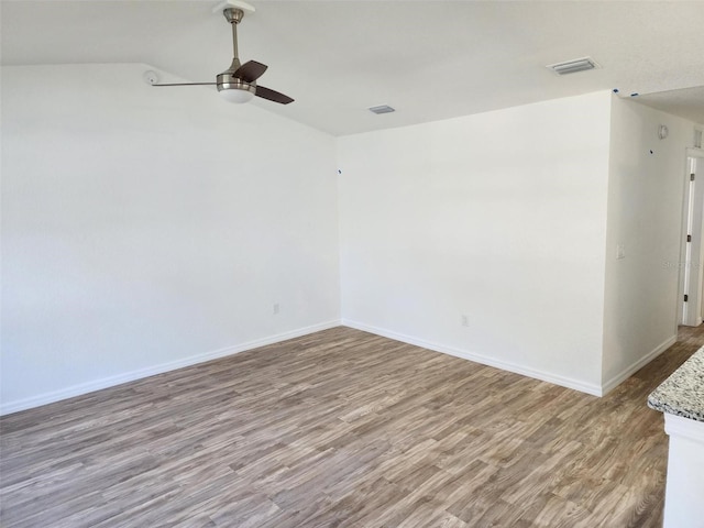 spare room with hardwood / wood-style flooring, vaulted ceiling, and ceiling fan