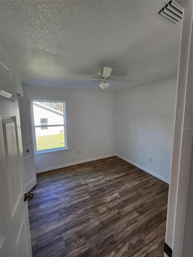 unfurnished room featuring ceiling fan, dark hardwood / wood-style flooring, and a textured ceiling