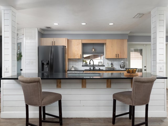 kitchen featuring dark hardwood / wood-style flooring, a breakfast bar, sink, and black fridge with ice dispenser