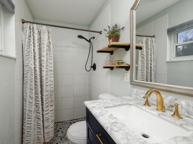 bathroom featuring walk in shower, vanity, toilet, and a textured ceiling