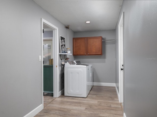 laundry area featuring independent washer and dryer, cabinets, light hardwood / wood-style flooring, and a textured ceiling