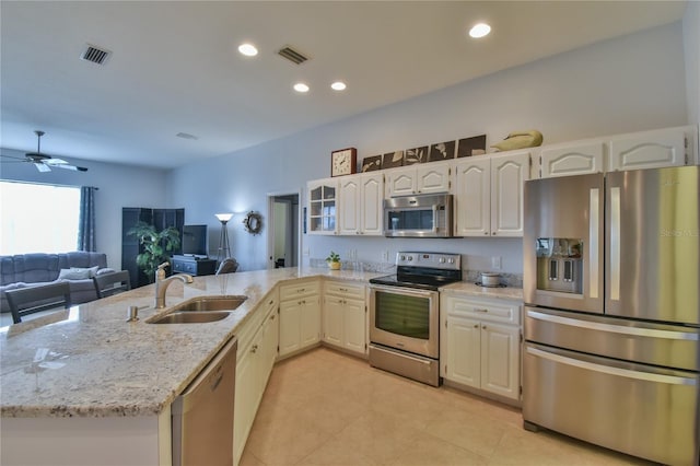 kitchen featuring kitchen peninsula, stainless steel appliances, light stone counters, and sink