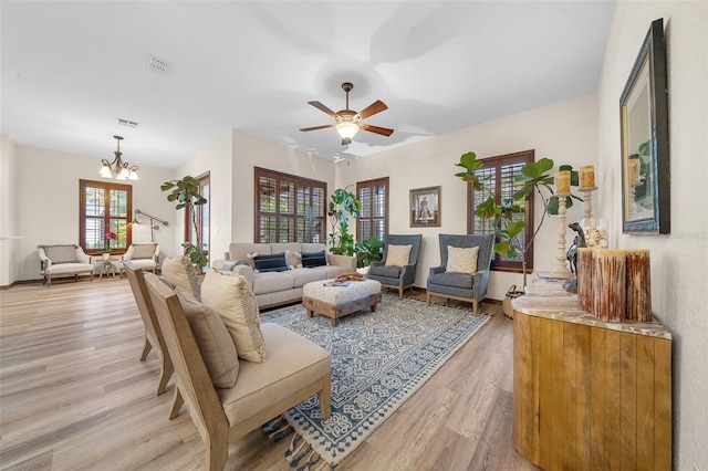 living room with ceiling fan with notable chandelier and wood-type flooring