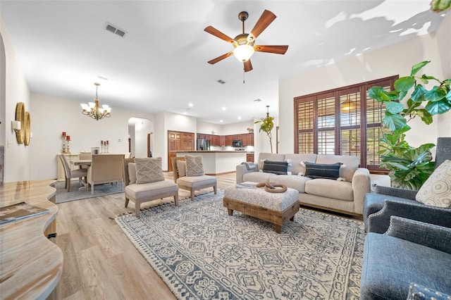 living room featuring ceiling fan with notable chandelier and light hardwood / wood-style flooring