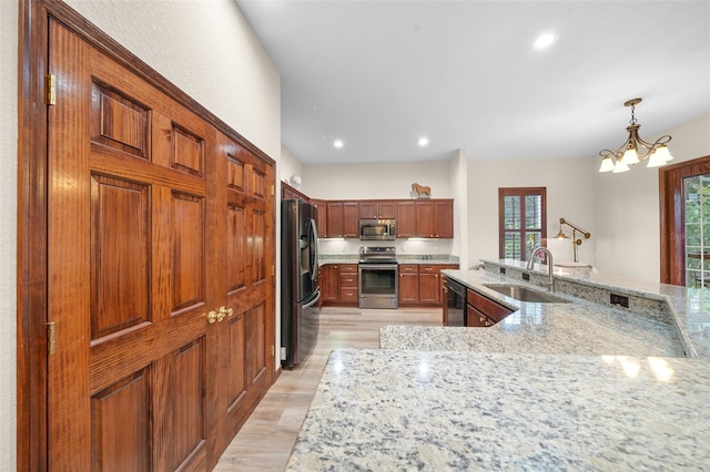 kitchen featuring pendant lighting, sink, appliances with stainless steel finishes, light stone counters, and a chandelier