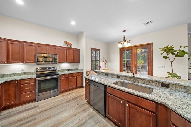 kitchen with light stone countertops, stainless steel appliances, sink, light hardwood / wood-style flooring, and an inviting chandelier