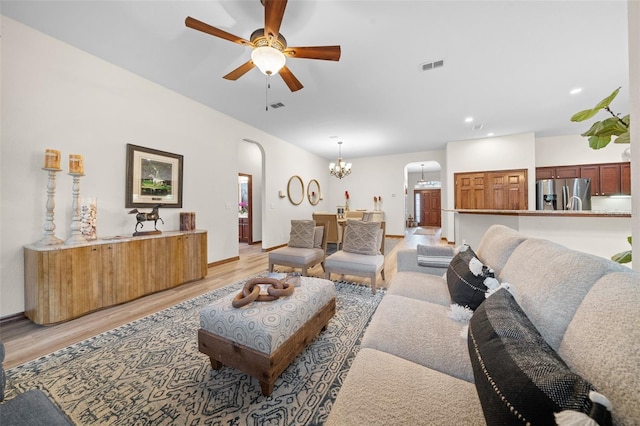 living room with ceiling fan with notable chandelier and light hardwood / wood-style flooring