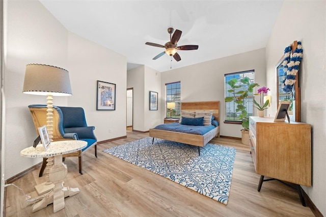 bedroom with ceiling fan, a fireplace, and light hardwood / wood-style flooring