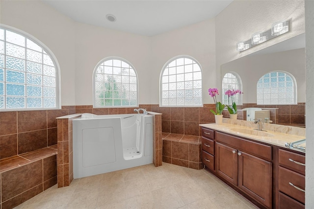 bathroom featuring vanity, tile patterned floors, tile walls, and a tub