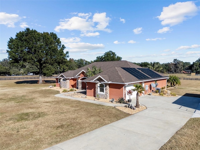 single story home with a garage, a front yard, and solar panels