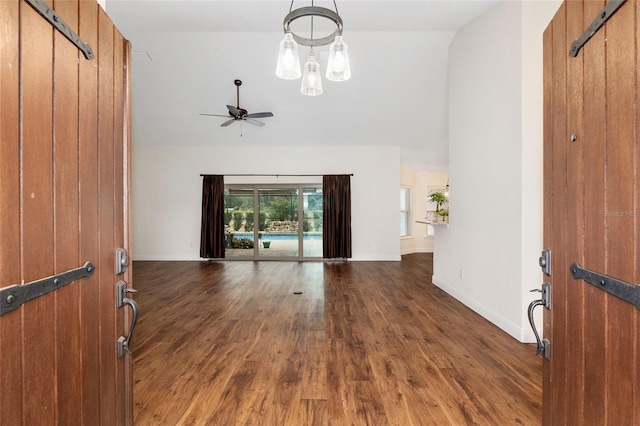 unfurnished living room with ceiling fan, dark wood-type flooring, and vaulted ceiling