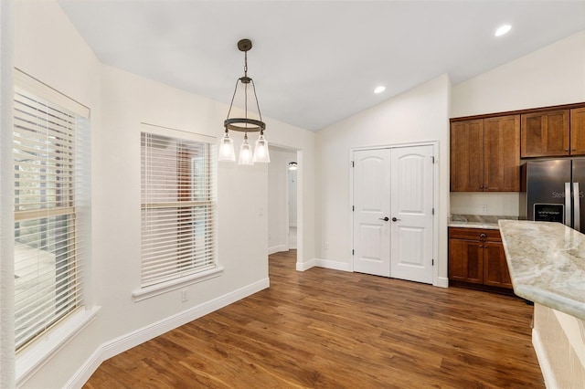 kitchen featuring dark wood-type flooring, a notable chandelier, stainless steel fridge with ice dispenser, hanging light fixtures, and lofted ceiling