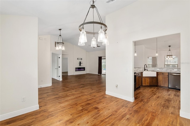 kitchen with dishwasher, hardwood / wood-style floors, vaulted ceiling, and pendant lighting