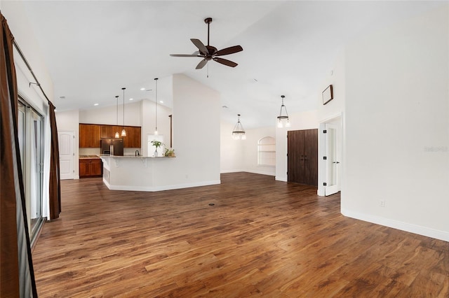 unfurnished living room featuring ceiling fan, dark wood-type flooring, and high vaulted ceiling