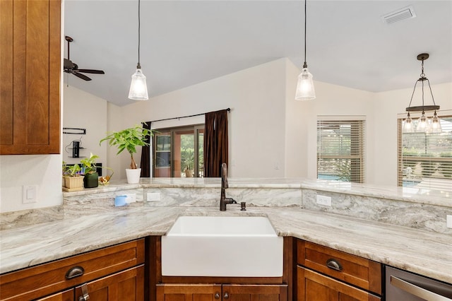 kitchen with pendant lighting, ceiling fan, light stone countertops, and sink