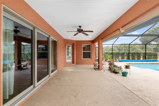 view of patio featuring ceiling fan, glass enclosure, and a covered pool