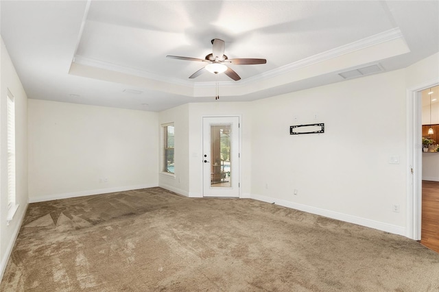 carpeted empty room with ceiling fan, a raised ceiling, and crown molding