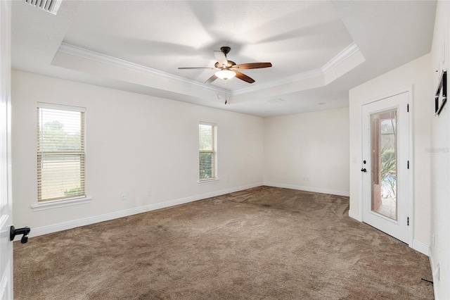 carpeted empty room with a tray ceiling, plenty of natural light, and crown molding