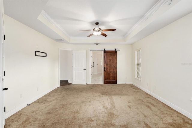 unfurnished bedroom with carpet, ceiling fan, a barn door, and a tray ceiling