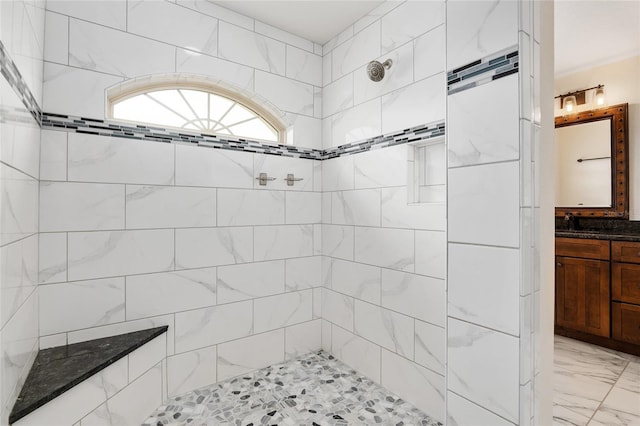 bathroom with a tile shower and vanity