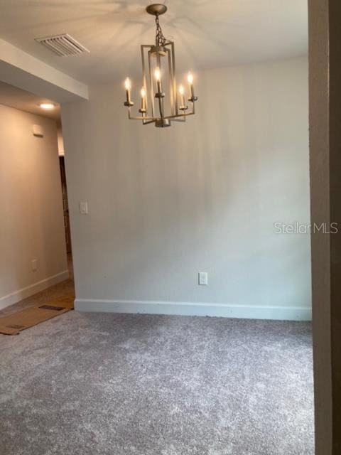 carpeted empty room with a notable chandelier