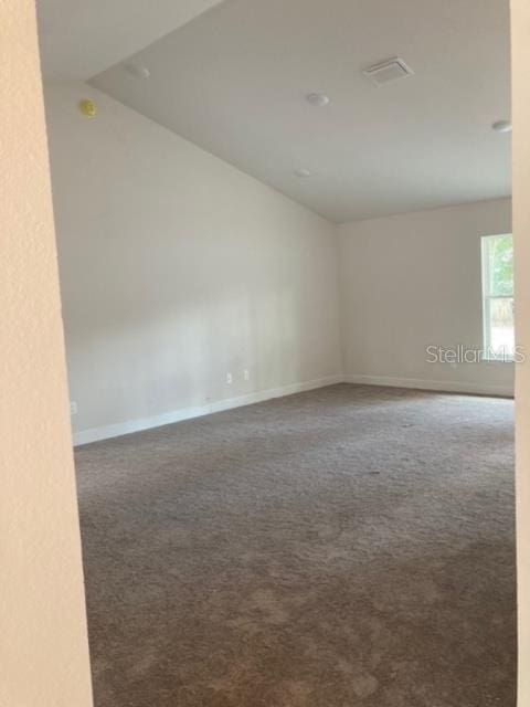 empty room featuring carpet and lofted ceiling