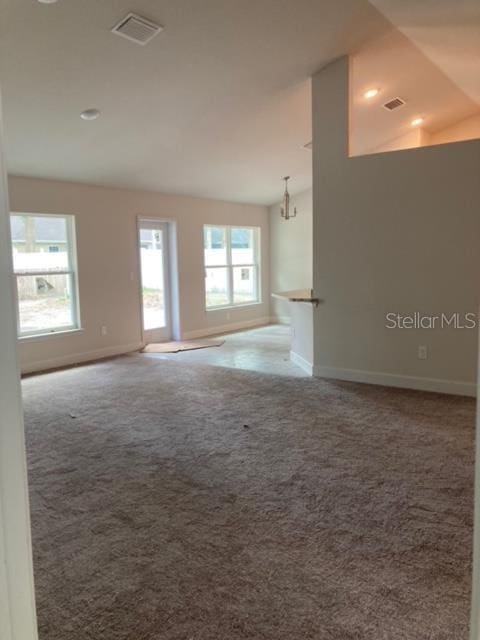 unfurnished living room with a notable chandelier and carpet floors