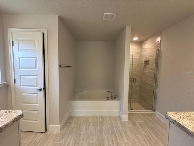 bathroom with separate shower and tub, vanity, wood-type flooring, and a textured ceiling