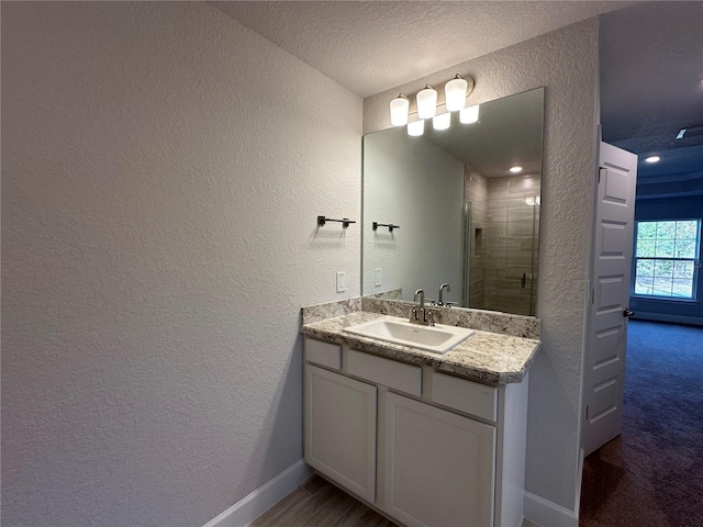 bathroom with a textured ceiling, vanity, and an enclosed shower