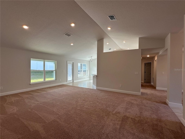 unfurnished living room featuring light carpet, a textured ceiling, and high vaulted ceiling