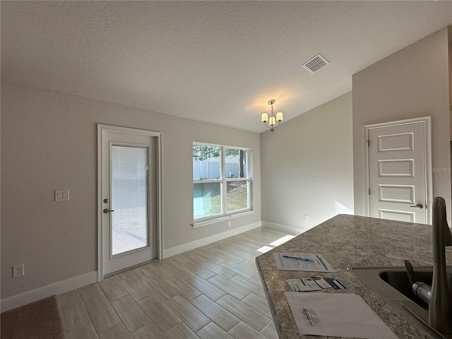 unfurnished dining area with a chandelier and a textured ceiling