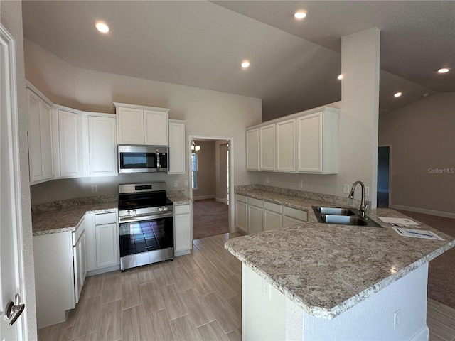 kitchen with kitchen peninsula, stainless steel appliances, white cabinetry, and sink