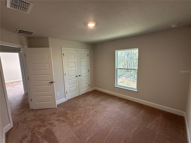 unfurnished bedroom with a closet, carpet floors, and a textured ceiling