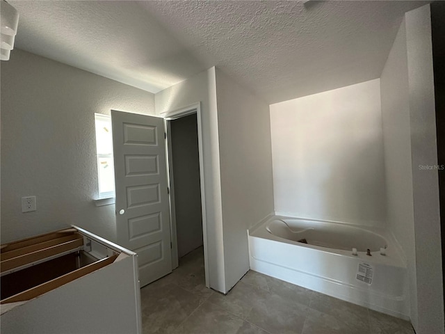 bathroom with tile patterned floors, a bath, and a textured ceiling